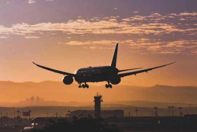 夕暮れの空港に着陸する旅客機の写真。航空業界の人材不足対策、特定技能採用、整備・運航支援の記事に最適な画像。