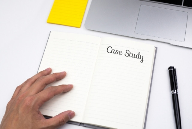 ノートに「Case Study」と書かれたページを開く手元。特定技能での雇用事例や分析の場面を表現。