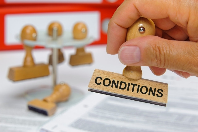 労働条件の確認を象徴する印章のイメージ。契約書に「CONDITIONS」と書かれたスタンプを押す場面。