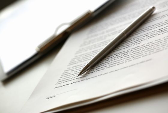 契約書の上に置かれたボールペン。雇用契約や在留手続きなど、外国人採用に関する書類署名のイメージ。