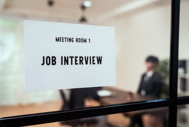 面接室のドアに「JOB INTERVIEW」の案内が貼られた写真。採用面接や外国人材の採用プロセス解説に適した画像。