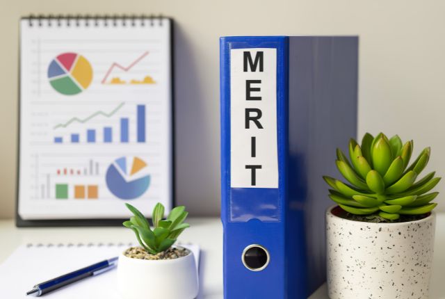 メリット 青いファイルと観葉植物、グラフ資料が並ぶデスク。外国人雇用のメリットを整理したオフィスイメージ。