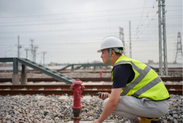 鉄道作業員 線路沿いで点検作業を行う鉄道技術者。特定技能「鉄道」分野の安全確認とインフラ保守の現場を示す。