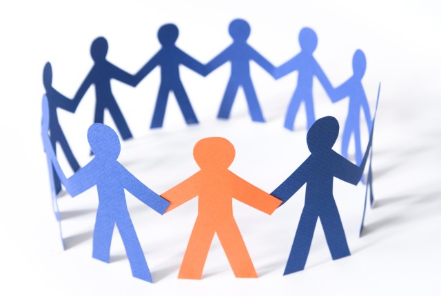 受け入れ企業の支援体制 青とオレンジの紙人形が手をつなぐ輪。鉄道業界における外国人材と日本人の協働・多文化共生を象徴。