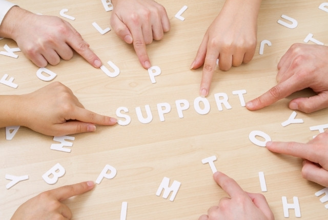 複数の手が「SUPPORT」の文字を指す写真｜特定技能ビザ申請に必要な生活支援・就労サポートのイメージ