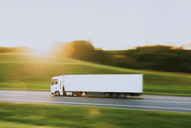 夕陽の中を走る大型トラック。物流や長距離輸送を象徴し、自動車運送業やドライバー採用のイメージに最適。