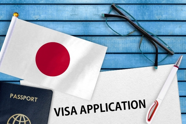 日本国旗とパスポート、VISA APPLICATIONと書かれた書類の写真｜特定技能ビザ申請手続きのイメージ
