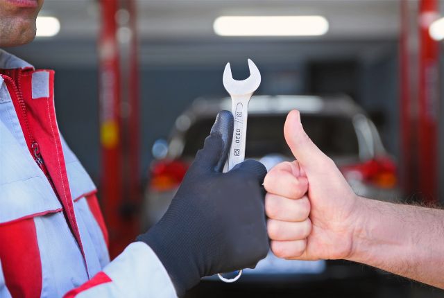 整備士がスパナを受け取り、利用者が親指を立てて評価する場面を写した写真｜自動車整備イメージ用