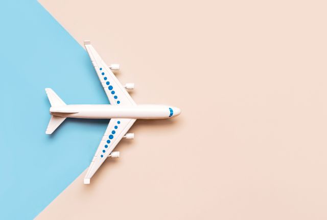 航空業界の特定技能2号採用ガイド用。白い旅客機が青とベージュの背景上を飛ぶイメージ写真。