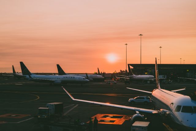 夕暮れの空港で複数の旅客機が駐機する様子。航空業界の業務や空港運営を示すイメージ写真。