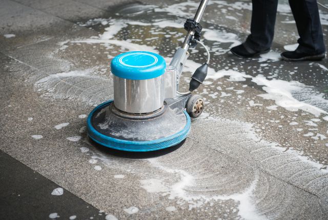 ポリッシャーで床面を洗浄する清掃作業の様子。ビルクリーニングや特定技能2号試験の実技内容を示す写真。