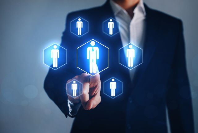 スーツ姿の人物が人材アイコンを指す画像。人材派遣会社の選定や採用プロセスを示すビジュアル