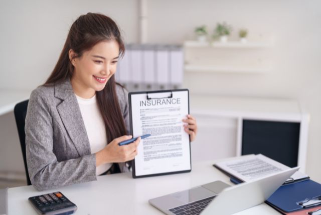 保険についての説明をしている事前ガイダンスの様子 保険書類を示しながら内容を説明するビジネス女性のイメージ。オンライン相談や手続き案内の場面。