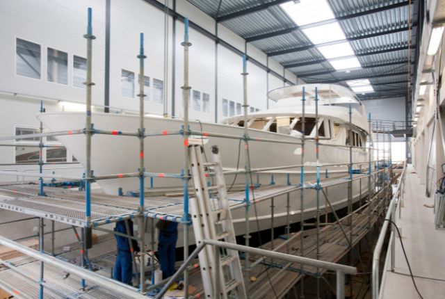 造船工場で建造中の大型船舶と足場で作業する技術者。特定技能2号の業務現場を示すイメージ。