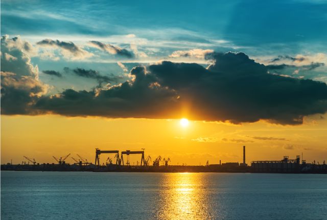 夕暮れの造船所と海を望む風景。クレーンが並ぶ造船・舶用工業の生産拠点を象徴するイメージ。