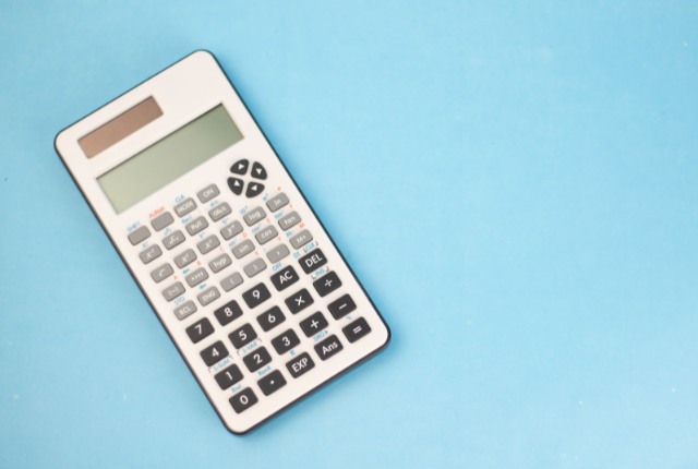 青い背景の上に置かれた電卓。技能実習生受入費用や管理費、消費税計算をイメージしたシンプルな構図。