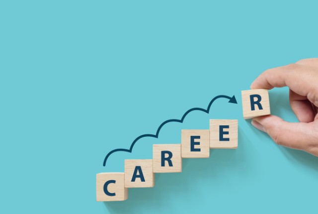 青い背景に「CAREER」と書かれた積み木を並べ、矢印が上向きに伸びている。キャリアアップや人材育成を象徴するイメージ。