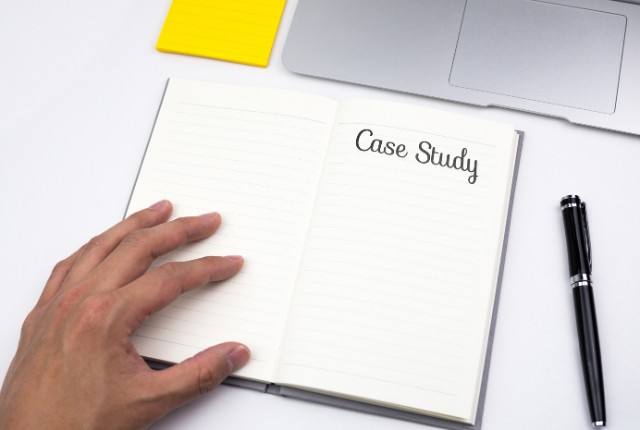 事例紹介 「Case Study」と書かれたノートを開く手元。外国人雇用の成功事例や導入ケースをまとめるイメージ。