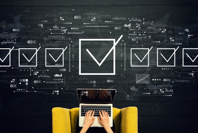 ノートパソコンを操作する人の前にチェックリストのアイコンが並ぶ。助成金申請や補助金手続きの確認作業を表すイメージ。