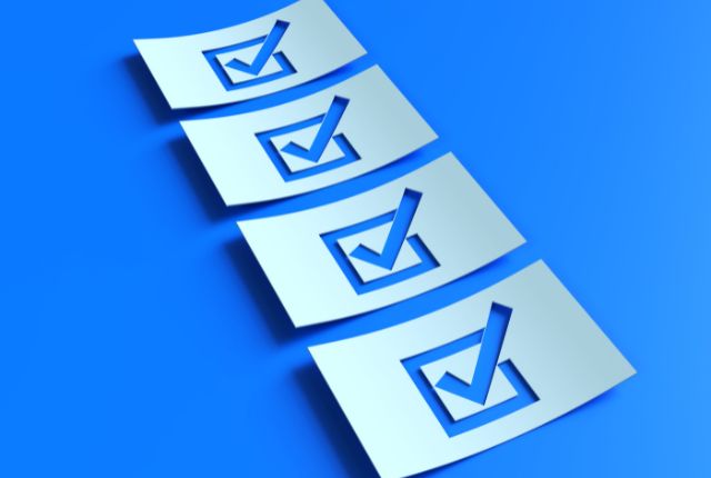 海外就職の確認項目 青い背景に並んだチェックマーク入りのリストカード。タスク管理や準備項目の確認を表すイメージ写真