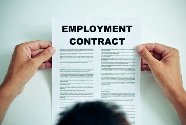 雇用契約書 雇用契約書を手に持つ人物の上からの視点。外国人材の雇用手続きや契約内容を示すイメージ。