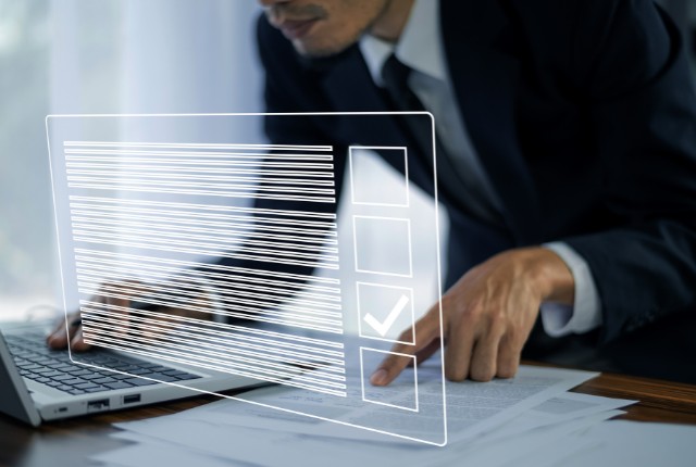 パソコンで書類を確認するビジネスマン。特定技能制度の申請手続きや在留資格管理のイメージ。