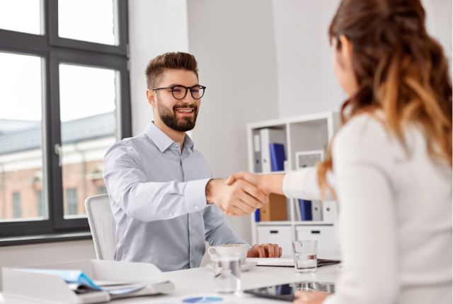外国人材の雇用契約 オフィスで面接後に握手を交わす男女。採用決定や外国人雇用の成功、ビジネスパートナー契約のイメージ