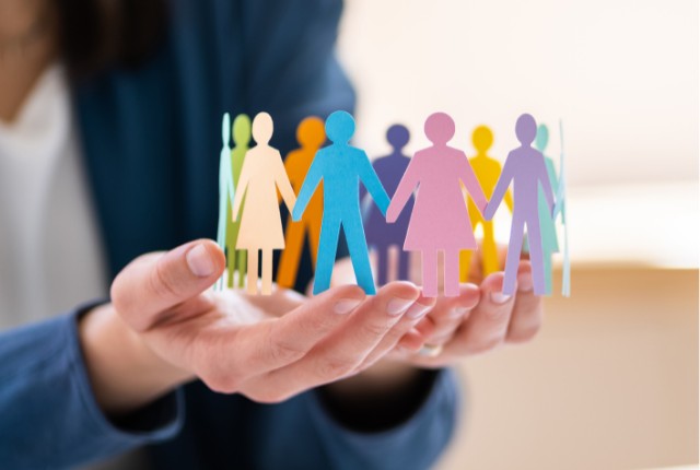 多様な人々を象徴するカラフルな紙人形を手に持つ人物。多文化共生や外国人雇用のダイバーシティ推進を表すイメージ。