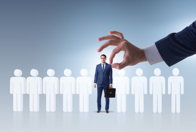 外国人材雇用の課題点 スーツ姿の男性が候補者の中から選ばれているイメージ。人材採用や外国人雇用の選考プロセスを象徴。