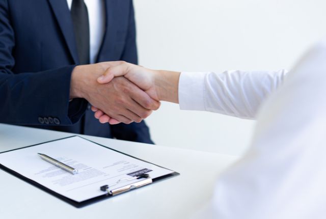 面接後に握手を交わすビジネスシーン。新卒外国人採用や留学生採用における内定・採用決定の瞬間を示すイメージ。