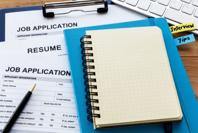 履歴書やジョブアプリケーション用紙、ノートが並ぶデスクの写真。外国人材採用や採用手続きの準備をイメージできる構図。