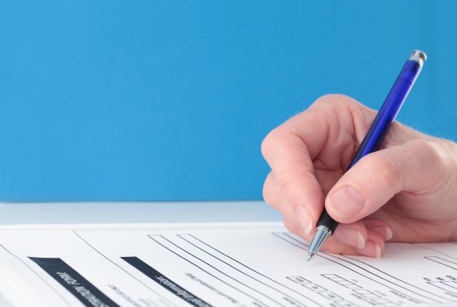 回答用紙ににボールペンで記入する手元の写真。特定技能制度の試験に関するイメージに適した画像。
