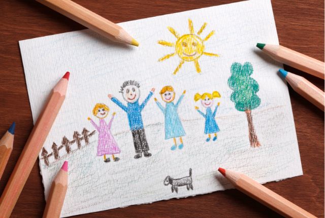子どもが描いた家族の絵。太陽の下で笑顔の家族と犬が描かれ、家族愛や子どもの成長、家族帯同制度を象徴