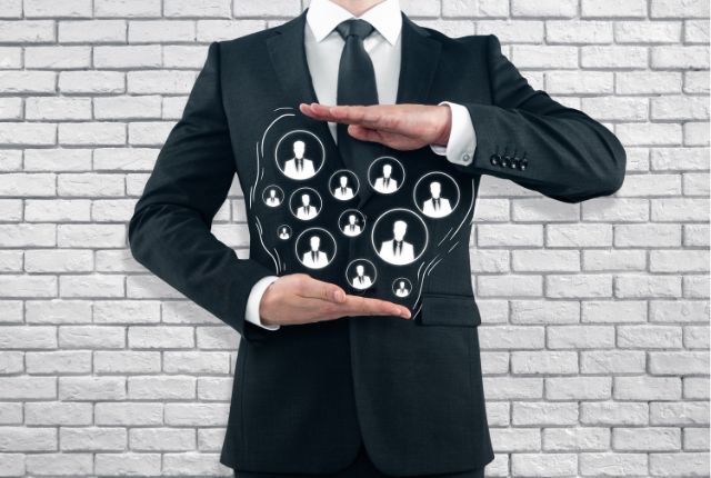 スーツ姿のビジネスマンが人材ネットワークを象徴するイラストを手で囲む。外国人雇用や人材管理の概念を表現。