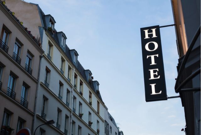 ホテルの外観と看板が写る街並みの写真。宿泊施設の外国人採用や人手不足対策に関連するイメージ。