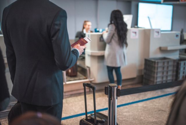 入国審査 空港のチェックインカウンターでパスポートを持つ旅行者が並んでいる場面。渡航手続きのイメージ写真。