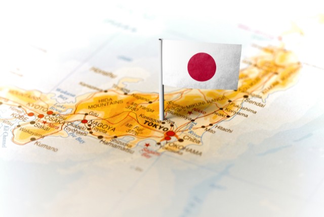日本地図の上に日の丸の国旗ピンが立っている。外国人雇用や国内支援制度、日本の助成金制度を示すイメージ。