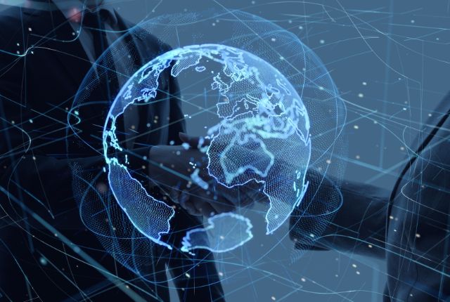 海外企業との雇用契約での握手 グローバルネットワークを象徴する地球のデジタル表示と、ビジネスパーソンの握手を重ねた国際取引のイメージ写真