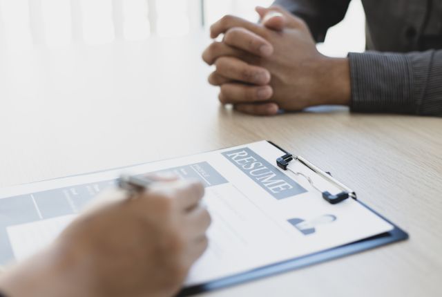 履歴書を確認しながら求職者と面接するシーン。採用選考や人材マネジメントを示すビジネス写真