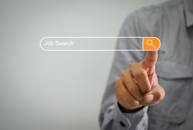 検索バーに『Job Search』と表示され、男性が検索アイコンをタップする様子。転職活動や求人検索をイメージした画像。