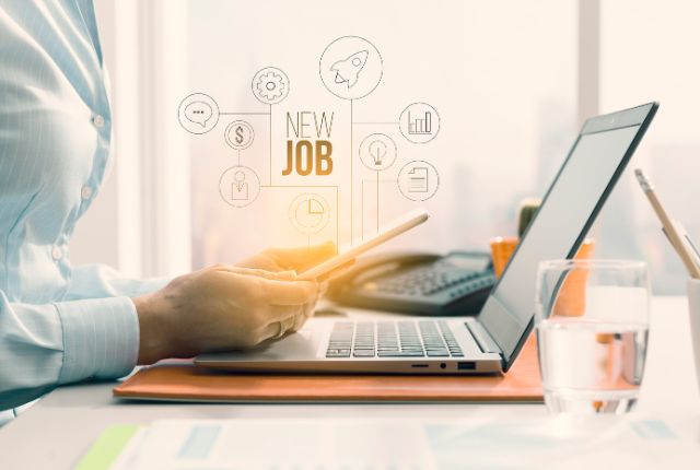 スマホとノートパソコンを使い新しい仕事を探すビジネスパーソンの手元の様子を示すイメージ。