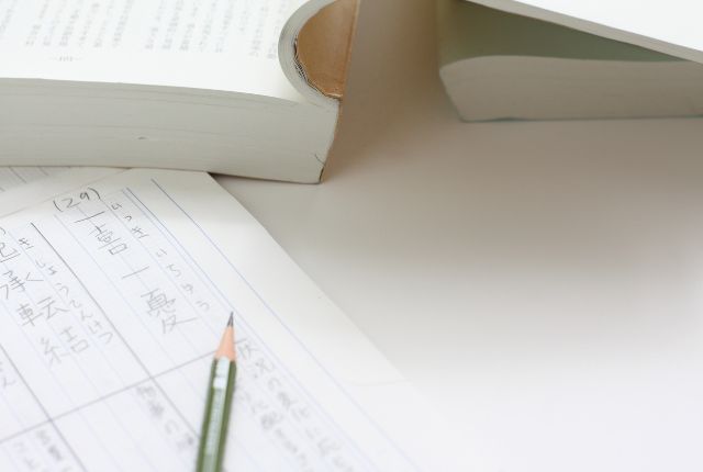 日本語のノートと鉛筆、参考書を使った学習風景の写真｜外国人材の日本語学習・試験対策イメージ用