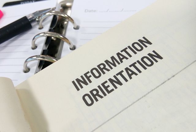 生活オリエンテーションの配布資料 生活オリエンテーション資料のページが開かれたノートとペンの写真。特定技能外国人支援に関する説明イメージ。