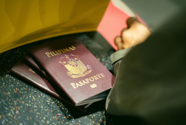 フィリピンのパスポートを手にする人物。特定技能や在留資格申請など外国人労働者受け入れを示す写真。