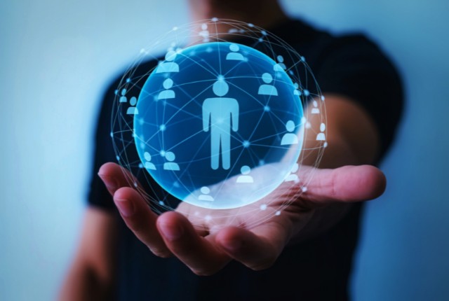 手のひらに浮かぶ青い球体に人のアイコンがつながるネットワークのイメージ。外国人材採用や人材活用の概念を表現。