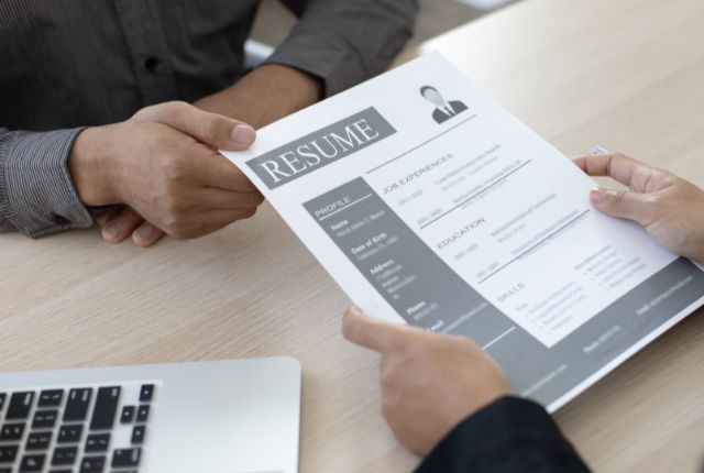 履歴書を面接官に手渡す場面を写した写真。人材紹介サービスや転職活動の流れを解説する記事用のイメージ。