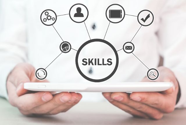タブレットを持つ手の上にスキル要素のアイコンが表示された図。ビジネススキルを示すイメージ。