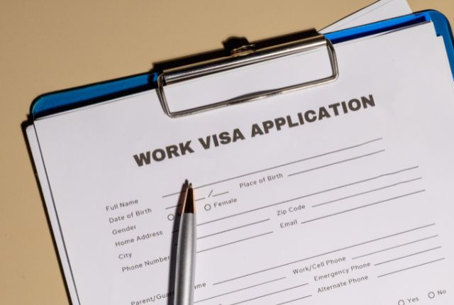 ビザの申請書類 外国人の就労ビザ申請書がクリップボードに置かれている様子。ペンが置かれ、申請手続きをイメージさせる構図。