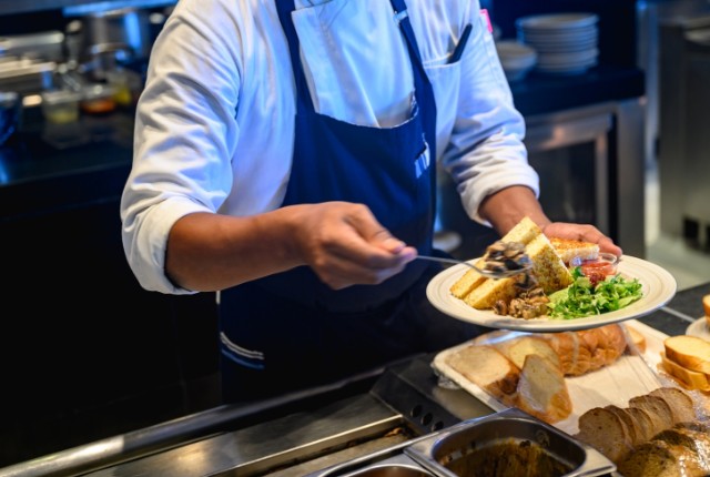 厨房で料理を盛り付けるシェフ。外食業における特定技能2号の調理スキルや実務経験を象徴するイメージ。