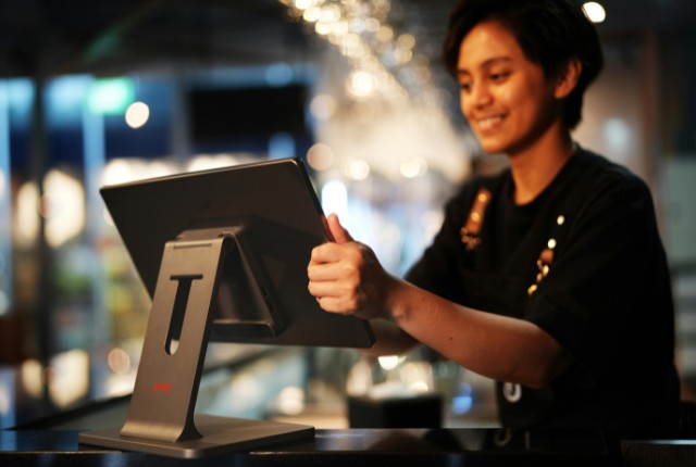 飲食店でタブレットPOSを操作するスタッフ。外食業の特定技能制度や店舗運営スキルのイメージ。